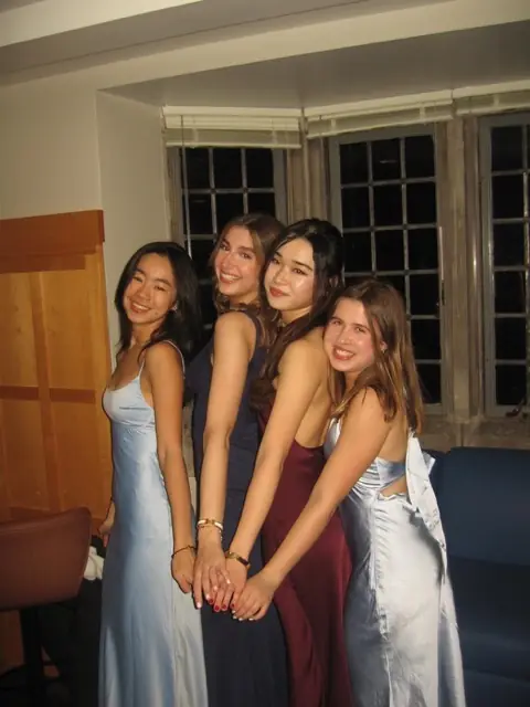 Four members in long dresses posing together indoors