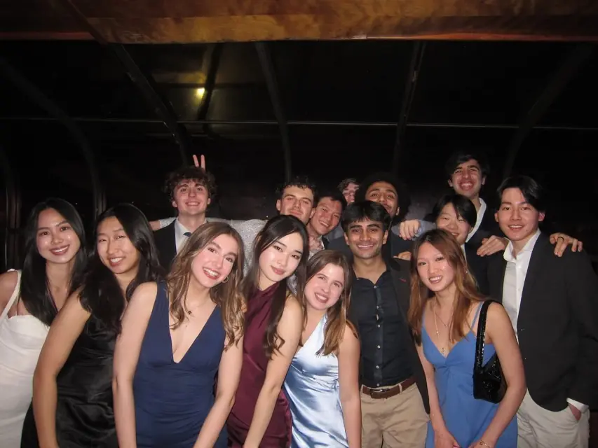 Members in cocktail dresses and suits grouped in a dimly lit room