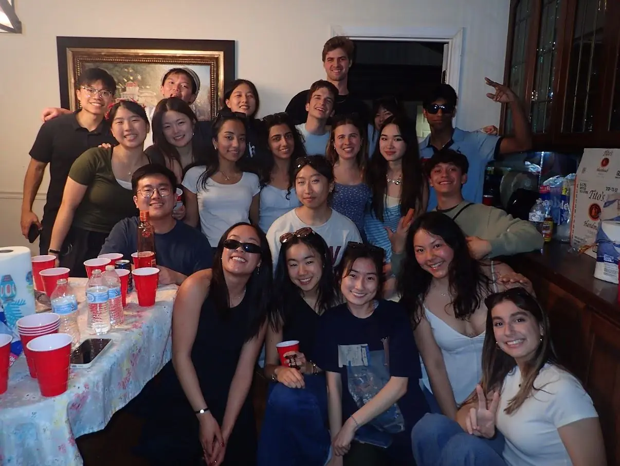 A big group around a table of red cups, smiling at the camera