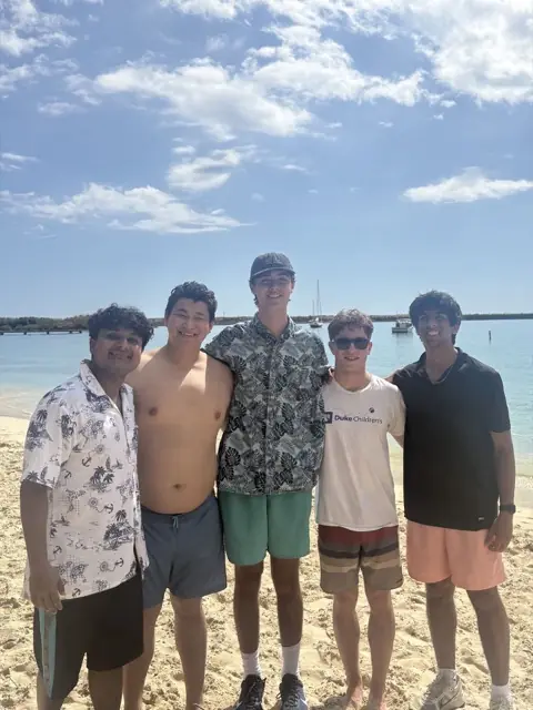Five members standing on a sunny beach
