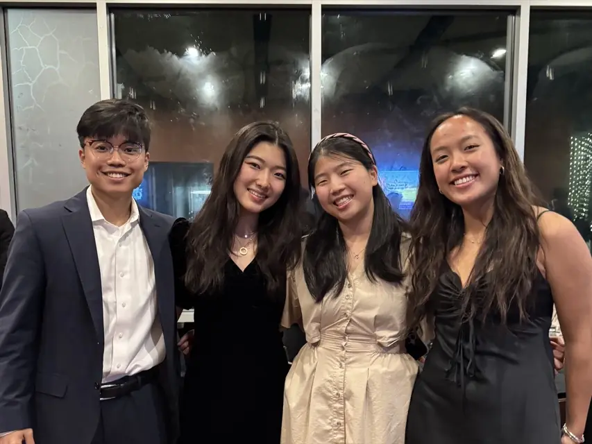 Four members in formal wear in front of large windows